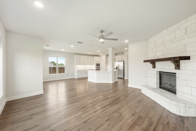 unfurnished living room featuring ceiling fan, hardwood / wood-style flooring, and a fireplace