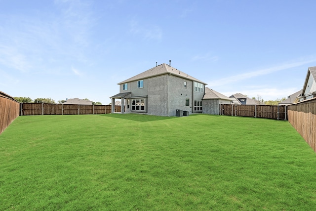 rear view of property with central air condition unit and a lawn