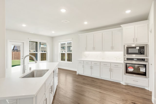 kitchen with white cabinetry, light hardwood / wood-style floors, appliances with stainless steel finishes, and sink