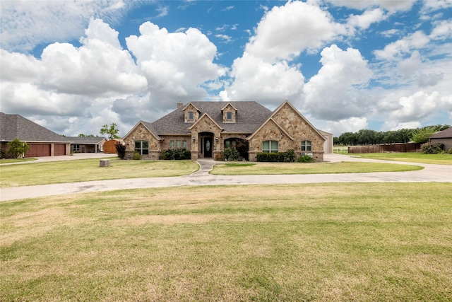 french country home featuring driveway, stone siding, brick siding, and a front yard