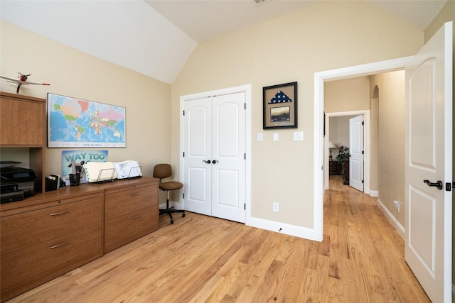 home office with light wood-type flooring, lofted ceiling, arched walkways, and baseboards