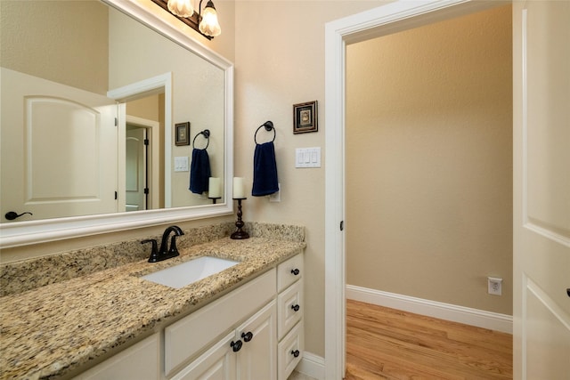 bathroom featuring baseboards, wood finished floors, and vanity