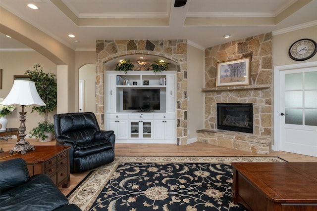 living room featuring a stone fireplace, ornamental molding, wood finished floors, and recessed lighting