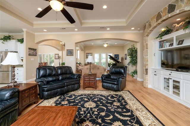 living area with a tray ceiling, visible vents, and a healthy amount of sunlight