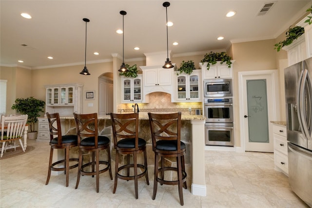 kitchen with visible vents, arched walkways, decorative backsplash, a kitchen breakfast bar, and stainless steel appliances