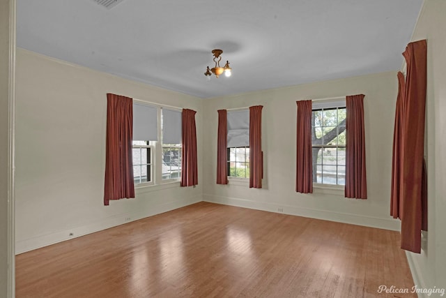 empty room featuring an inviting chandelier and light wood-type flooring