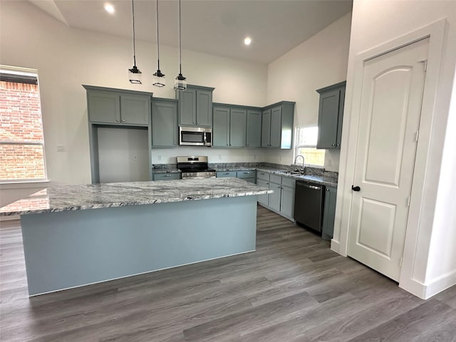 kitchen with sink, decorative light fixtures, light stone counters, dark hardwood / wood-style flooring, and appliances with stainless steel finishes