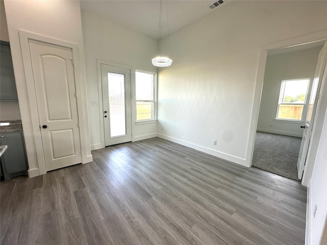 unfurnished dining area featuring wood-type flooring, a notable chandelier, and a healthy amount of sunlight