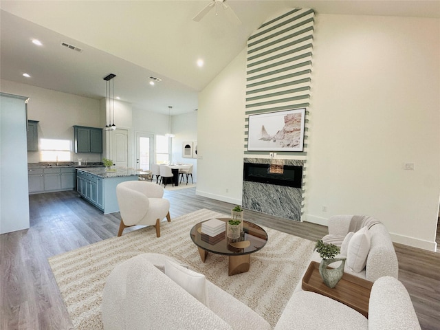 living room featuring ceiling fan, light hardwood / wood-style flooring, and high vaulted ceiling