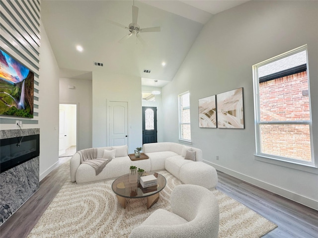 living room with a high end fireplace, high vaulted ceiling, ceiling fan, and dark hardwood / wood-style flooring