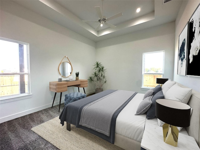 carpeted bedroom with multiple windows, ceiling fan, and a tray ceiling