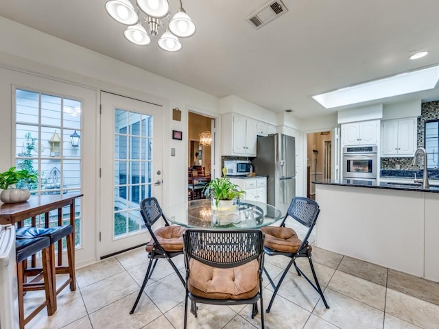 tiled dining room featuring sink and a chandelier