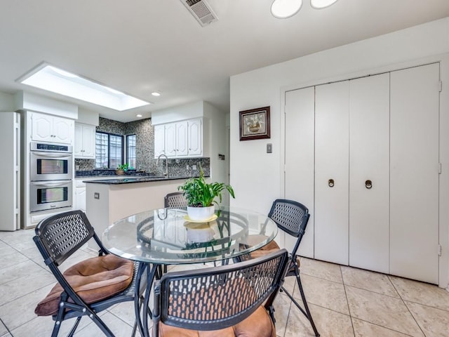 dining space with sink, a skylight, and light tile patterned floors