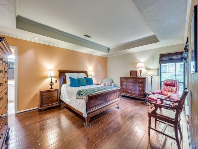 bedroom with ornamental molding, dark wood-type flooring, and a tray ceiling