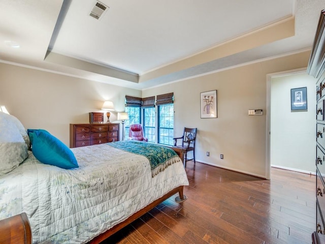 bedroom featuring dark wood-type flooring, a tray ceiling, and crown molding