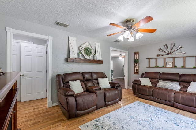 living room with ceiling fan, light hardwood / wood-style flooring, and a textured ceiling