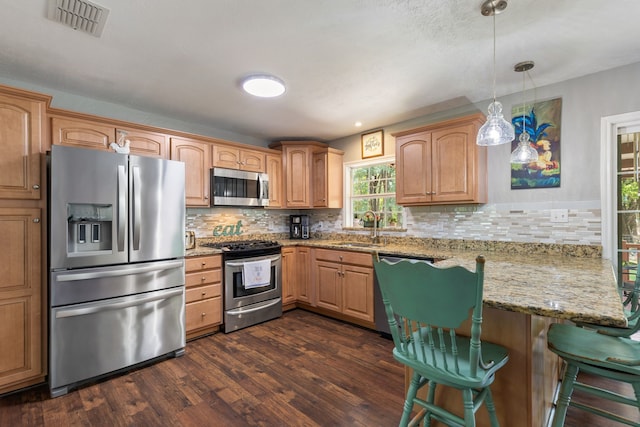 kitchen featuring appliances with stainless steel finishes, pendant lighting, sink, kitchen peninsula, and light stone countertops