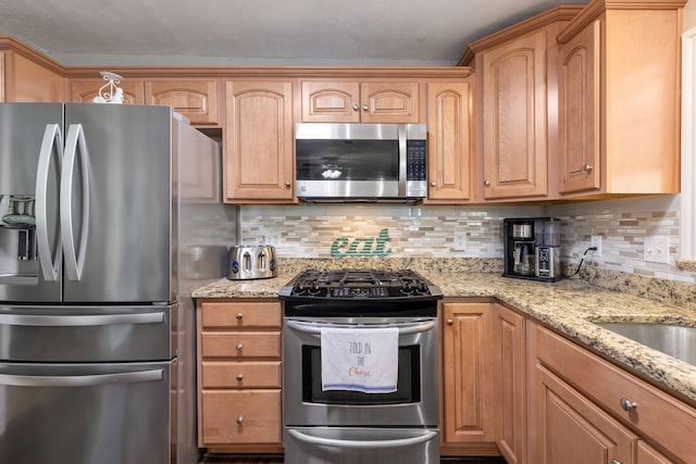 kitchen with tasteful backsplash, appliances with stainless steel finishes, and light stone countertops