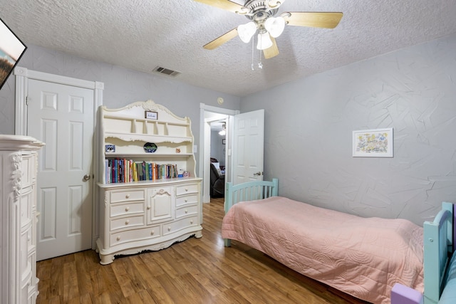 bedroom featuring ceiling fan, hardwood / wood-style floors, and a textured ceiling