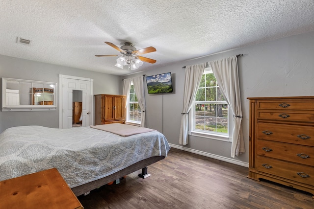 bedroom featuring ceiling fan, dark wood-type flooring, and a textured ceiling