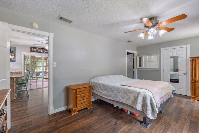 bedroom featuring ceiling fan, dark hardwood / wood-style floors, and a textured ceiling