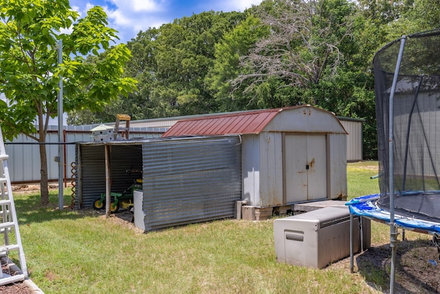 view of outbuilding featuring a trampoline and a lawn