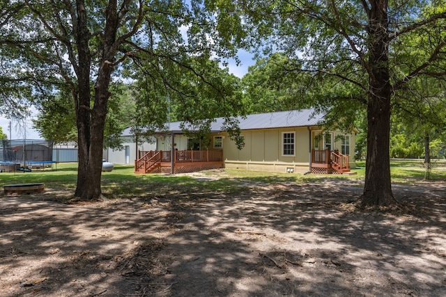 rear view of property featuring a deck and a trampoline