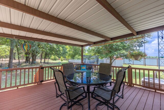 wooden terrace featuring an outbuilding, a lawn, a fenced backyard, cooling unit, and outdoor dining area