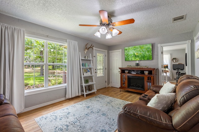 living room featuring a textured ceiling, ceiling fan, and light wood-type flooring