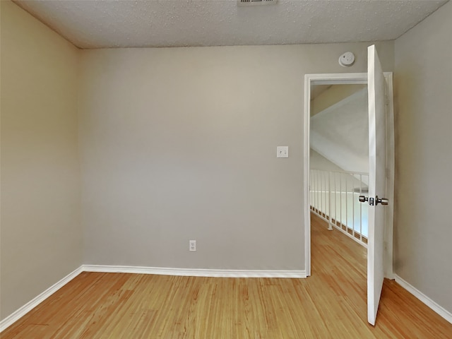 empty room with a textured ceiling, baseboards, and wood finished floors