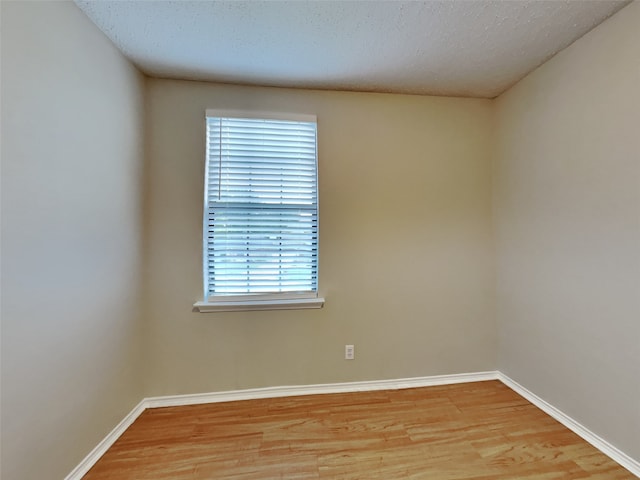 unfurnished room with light wood-style floors, baseboards, and a textured ceiling