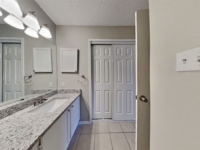 bathroom featuring a textured ceiling, baseboards, vanity, and tile patterned floors