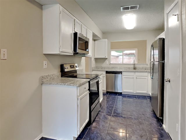 kitchen featuring white cabinets, visible vents, stainless steel appliances, and a sink