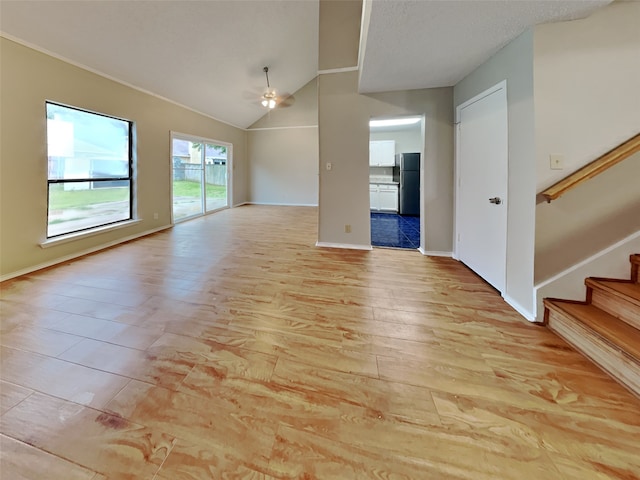 unfurnished living room with lofted ceiling, stairway, a ceiling fan, light wood-type flooring, and baseboards