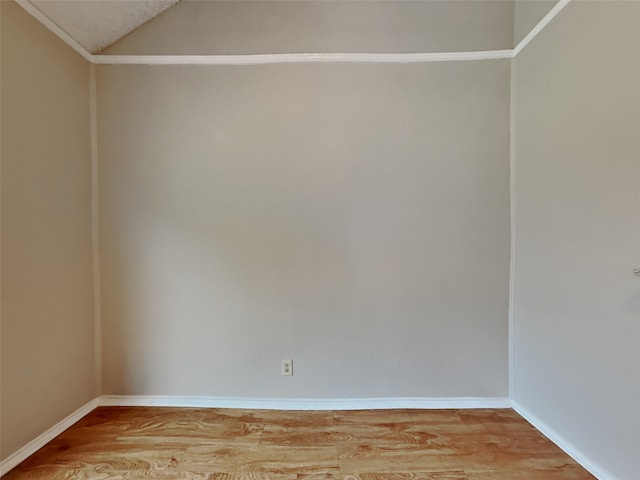 spare room with lofted ceiling, light wood-style flooring, and baseboards