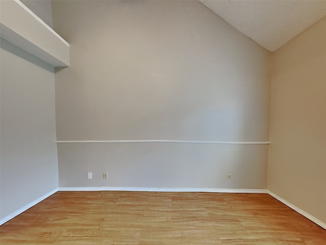 unfurnished room featuring lofted ceiling, light wood-style flooring, and baseboards