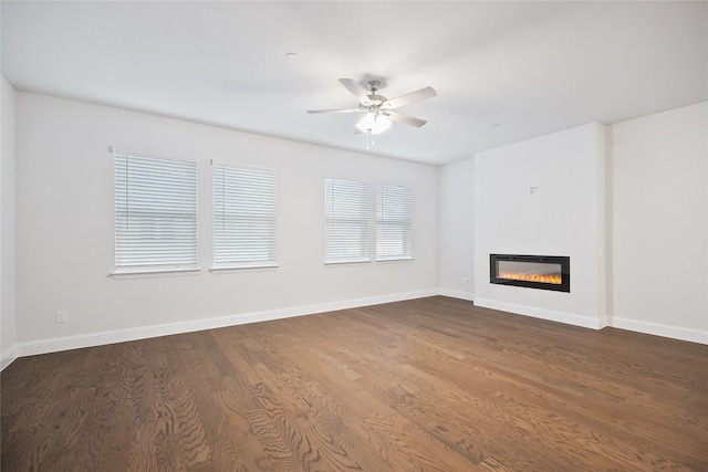 unfurnished living room featuring ceiling fan and dark wood-type flooring