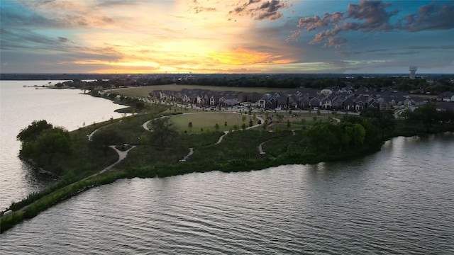 aerial view at dusk featuring a water view