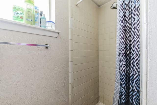 bathroom with tiled shower and a textured wall