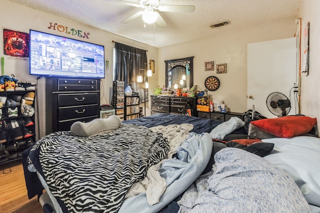 bedroom with a textured ceiling, hardwood / wood-style flooring, and ceiling fan