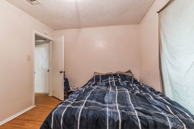 bedroom featuring light wood-type flooring and a textured ceiling