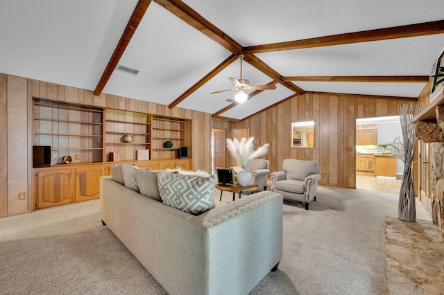 living area featuring light carpet, vaulted ceiling with beams, wooden walls, and a textured ceiling