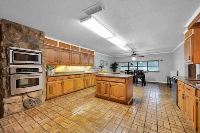 kitchen with visible vents, appliances with stainless steel finishes, ornamental molding, a center island, and tasteful backsplash