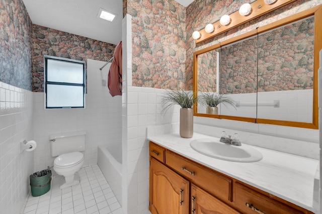 full bath with toilet, wainscoting, tile walls, and wallpapered walls