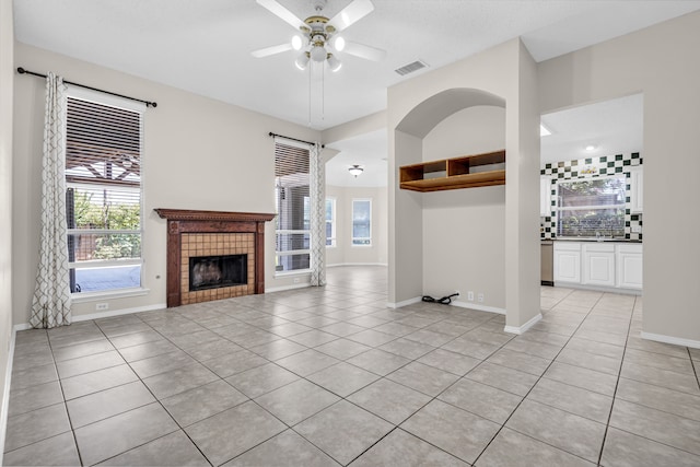 unfurnished living room with light tile patterned flooring, a fireplace, and ceiling fan