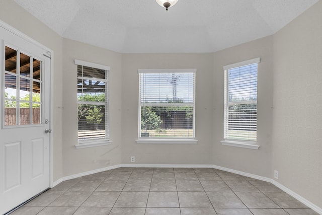 tiled spare room with a textured ceiling and a wealth of natural light