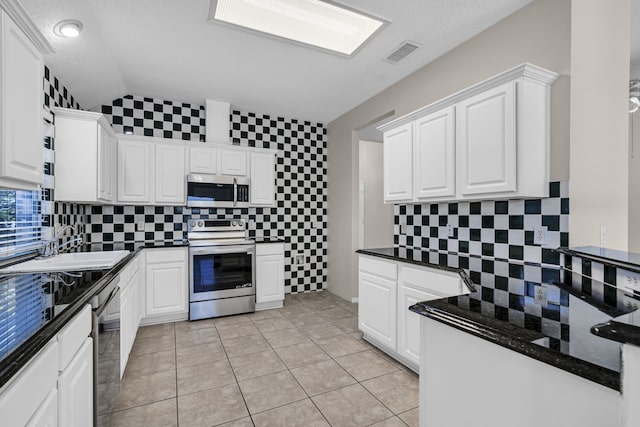 kitchen with light tile patterned flooring, tasteful backsplash, range with electric cooktop, and white cabinets