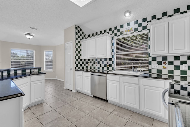 kitchen featuring stainless steel dishwasher, range, white cabinetry, and light tile patterned floors