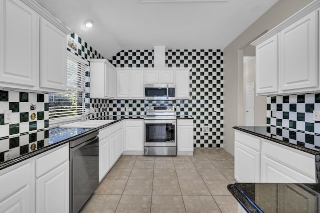 kitchen with white cabinetry, stainless steel appliances, backsplash, and light tile patterned floors