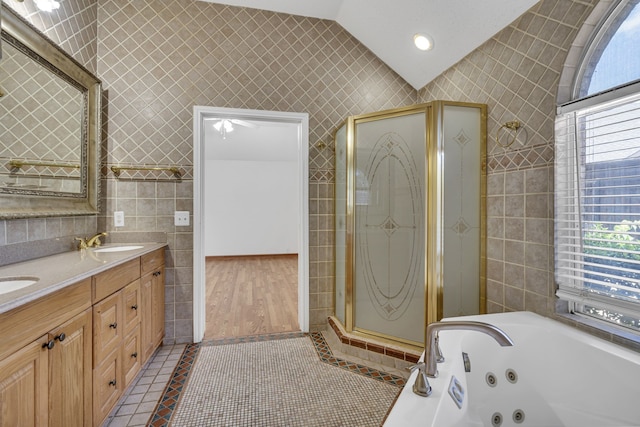 bathroom with tile walls, lofted ceiling, independent shower and bath, hardwood / wood-style flooring, and double sink vanity